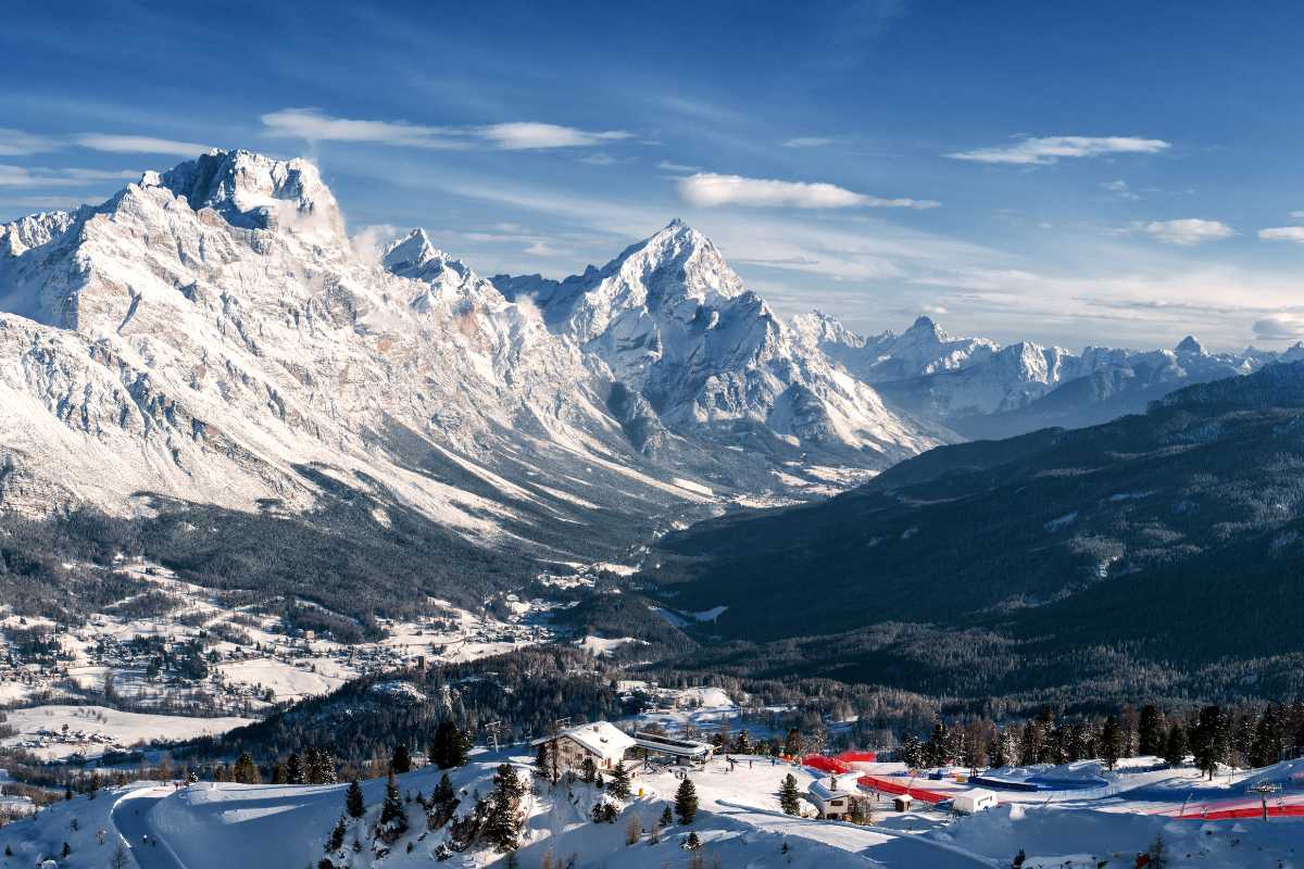 Escursionisti su sentiero panoramico estivo sopra Cortina, vista sulle Dolomiti, cielo azzurro, atmosfera di avventura e relax